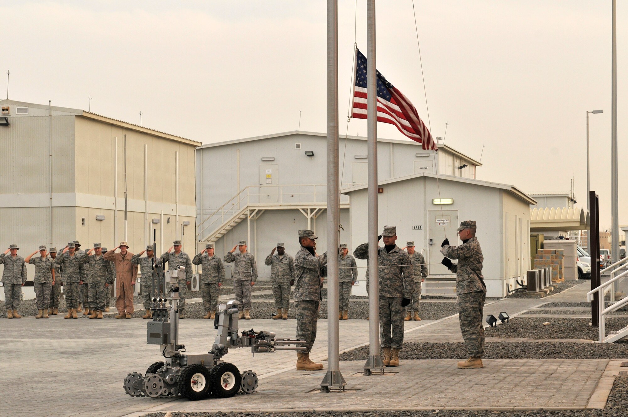 Lt. Col. William Kale III, 380th Expeditionary Civil Engineering Squadron Commander, takes the lead of this CE formation April 9 at an undisclosed location in Southwest Asia, but when an Air Force explosive ordinance disposal technician heads downrange, the robot goes first. Robotic systems like this one to the left of the flag have saved numerous lives by helping to eliminate the threat of improvised explosive devices encountered in deployed locations. The 380th Air Expeditionary Wing brings together active duty, reserve and Air National Guard Airmen joined with civilian patriots and DoD contractors to carry out its diverse mission of all-weather high-altitude ISR, airborne command and control and air refueling with a "One Team, One Fight" attitude. (U.S. Air Force Photo/Capt. Cathleen Snow/Released)