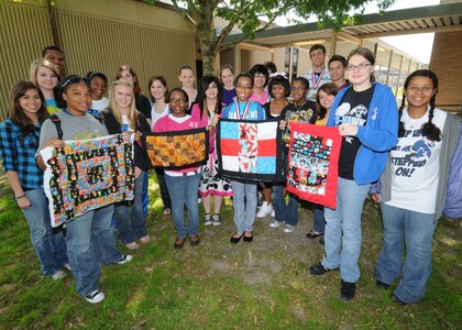 Students at Randolph Air Force Base High School display quilt samples made during a quilting project. THe students made larger quilts to donate to Project Linus for traumatized children. The quilting was done under the direction of RHS teacher Shirley McMenamin. (U.S. Air Force photo by Dave Terry)