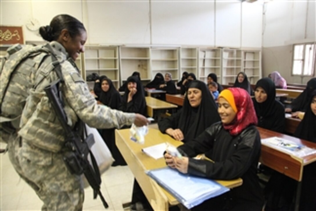 U.S. Army Sgt. Patricia Smith, with Forward Support Company, 2nd Battalion, 69th Armor Regiment, hands gifts to Iraqi women who are graduating from the widow beekeeping program at the Ibn Alhaytham Vocational School in Mussayibb, Iraq, on April 3, 2010.  A micro grant helps Iraqi widows start their own beekeeping businesses.  