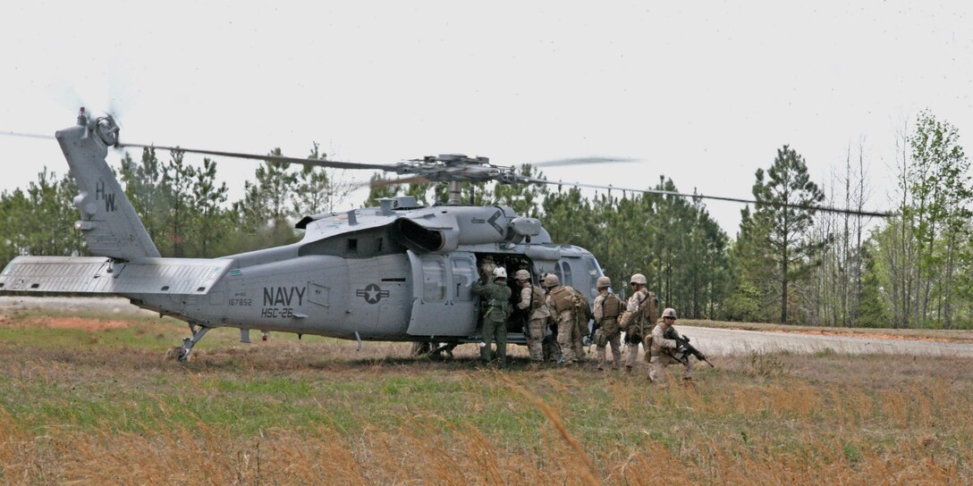 Marines from Company B, 1st Bn., 8th Marines, board a Navy MH-60S Knighthawk, with Helicopter Sea Combat Squadron 26, while a Marine provides security in the landing zone outside the Forward Operating Base Phoenix aboard National Guard Maneuver Training Center, Fort Pickett, Va., April 9, 2010.
