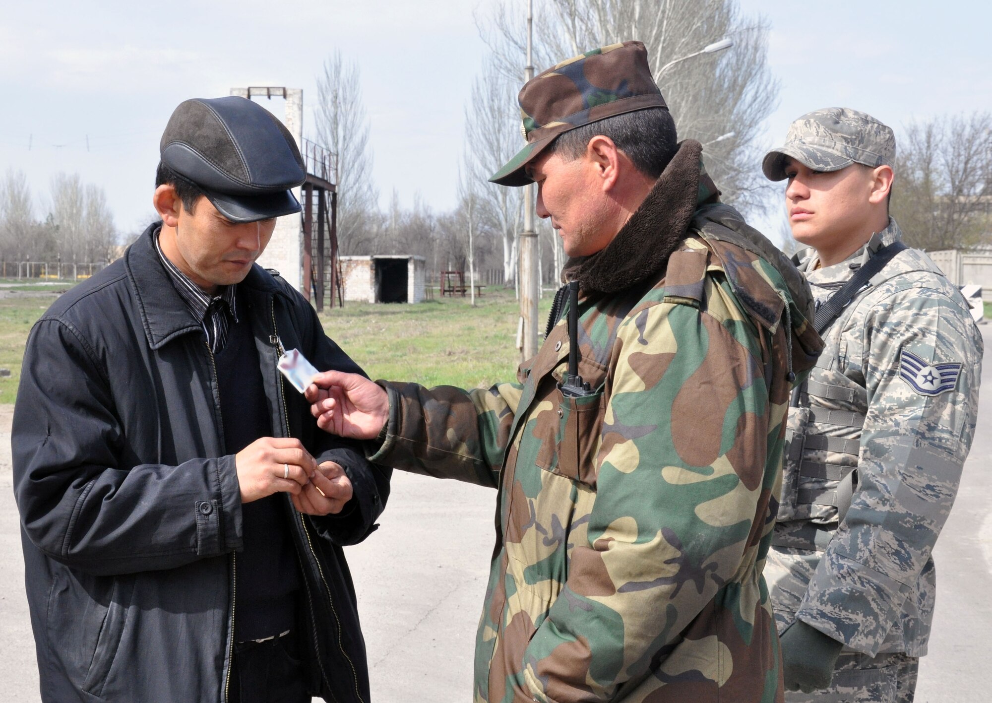 A Manas International Airport security member checks the credentials of a Kyrgyz pedestrian with U.S. Air Force Staff Sgt. Francisco Calzadillas at an entry control point between the airport and the Transit Center at Manas, Kyrgyzstan, April 10, 2010. Because of the unique mission of the Transit Center at Manas and the strategic U.S. presence in Kyrgyzstan, MIA personnel and 376th Expeditionary Security Forces Squadron members work closely together to ensure the safety and security of the Transit Center, the airport, and all of the members assigned to and working at both installations. (U.S. Air Force photo/Staff Sgt. Carolyn Viss/released)