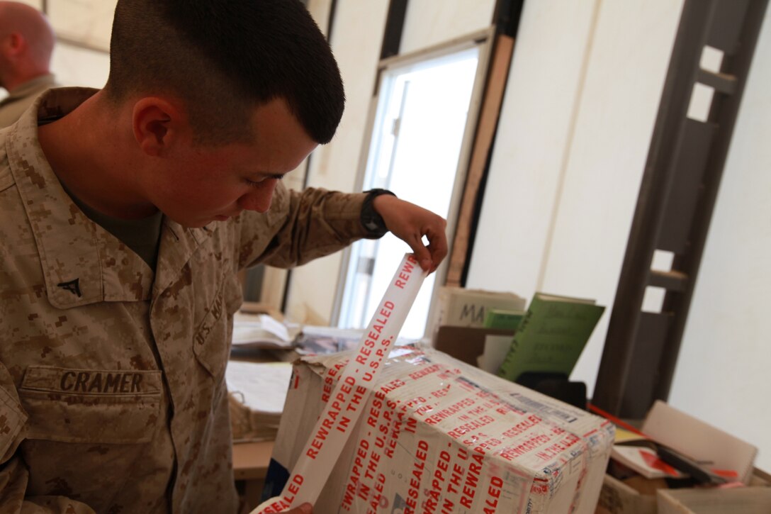 Lance Cpl. Matthew Cramer, a postal clerk with Headquarters and Service Company 1st Marines Logistics Group (Forward) reseals a package at the postal warehouse at Camp Leatherneck, Afghanistan, April 10. Kramer along with the other postal Marines keeps morale high by making sure service members receive their mail packages.