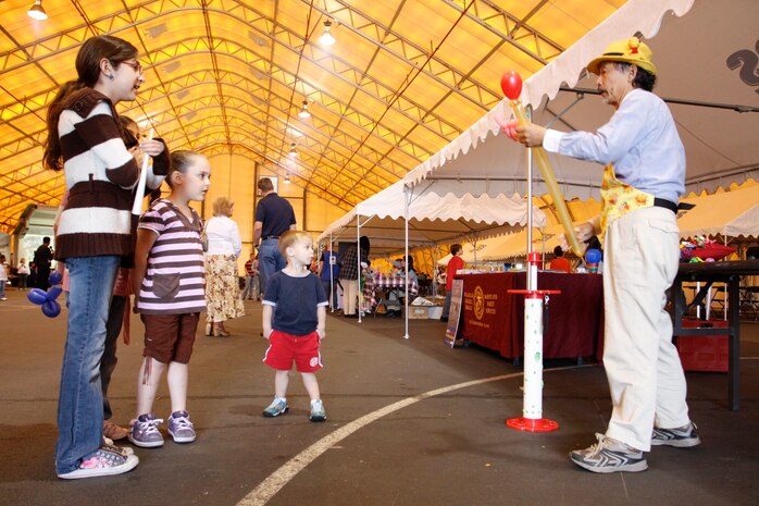 Isamu Froog, a professional balloonist, creates a balloon animal for Alex Cardenas and her younger sister Krista Cardenas during the Month of the Military Child celebration at the Multi-purpose Activity Center Dome here April 10. The purpose of the event was to recognize military children and families for all the sacrifices they make while parents and family members serve their country.