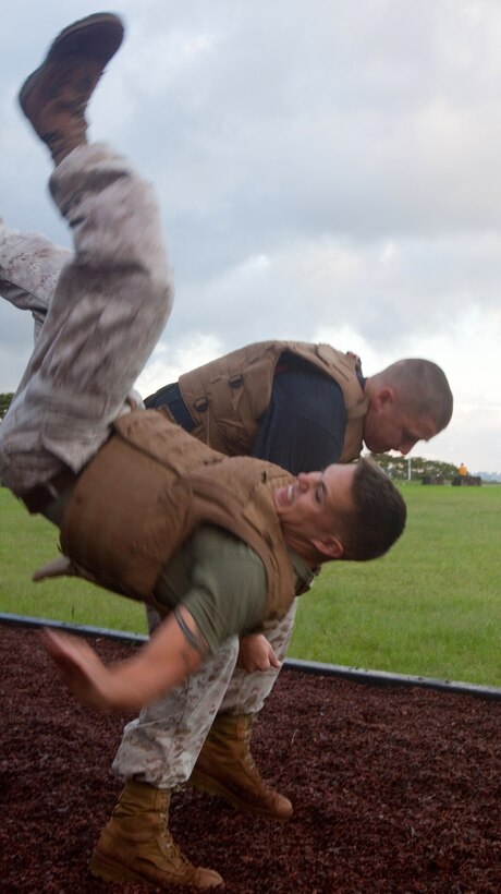 Sgt. Joseph M. Benezette, Marine Corps Martial Arts instructor trainer, demonstrates a shoulder throw on Sgt. Robert J. Porras, MCMAP instructor, during green belt training April 11 at Bordelon Field, Camp H. M. Smith, Hawaii. Porras and Benezette have taken the challenging of training 80 percent of Headquarters and Service Battalion, U.S. Marine Corps Forces, Pacific, to green belt before August.