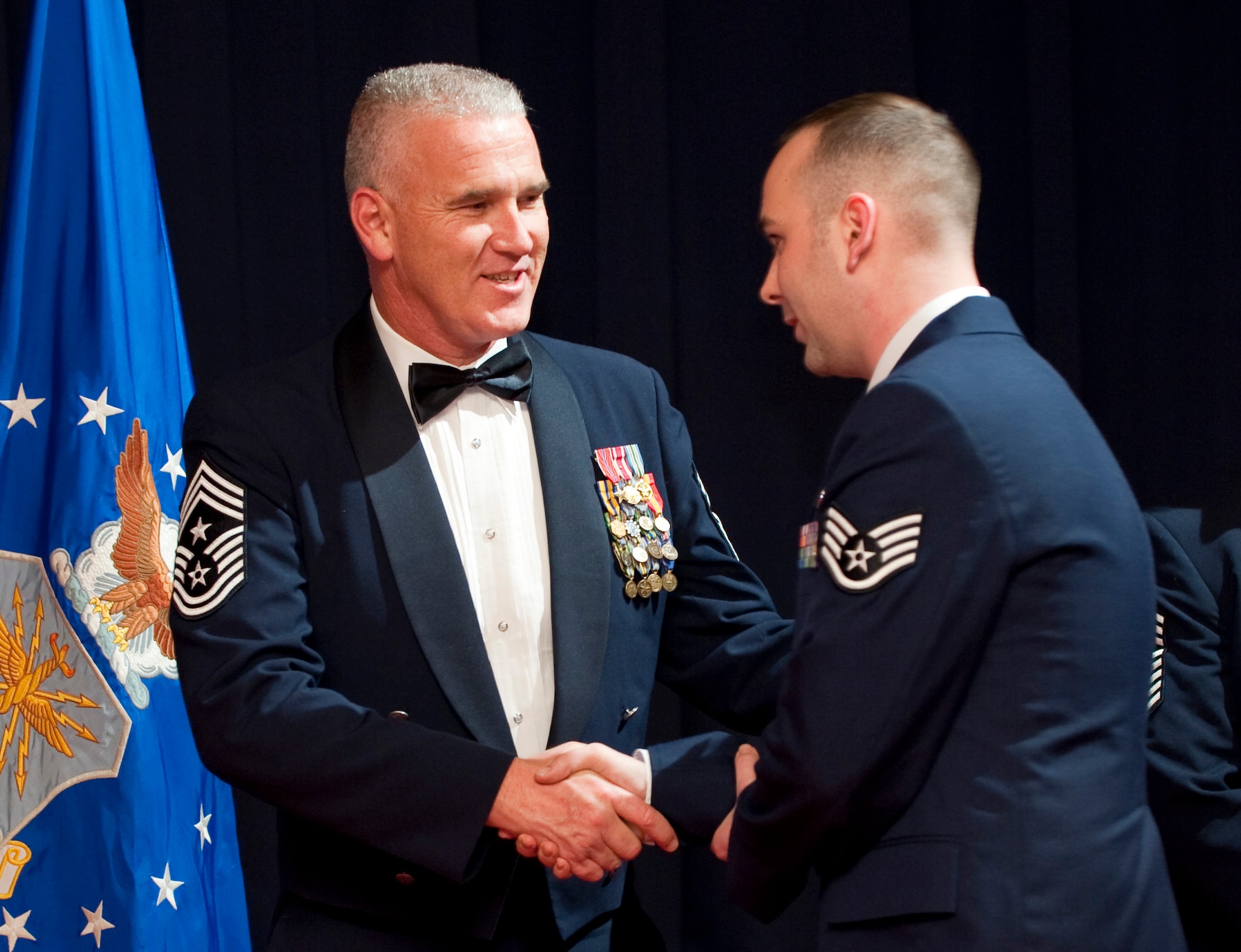 MISAWA AIR BASE, Japan -- Chief Master Sgt. Brook McLean, Pacific Air Forces command chief master sergeant, congratulates Staff Sgt. Patrick Lunsford, Airman Leadership School Class 10-C commander and distinguished graduate, on his graduation from Airman Leadership School April 8. Chief McLean spoke at the graduation, reminding the graduating Airmen of the important role they play as "sheepdogs" protecting the innocent from the "wolves" of the world. (U.S. Air Force photo/Staff Sgt. Samuel Morse)