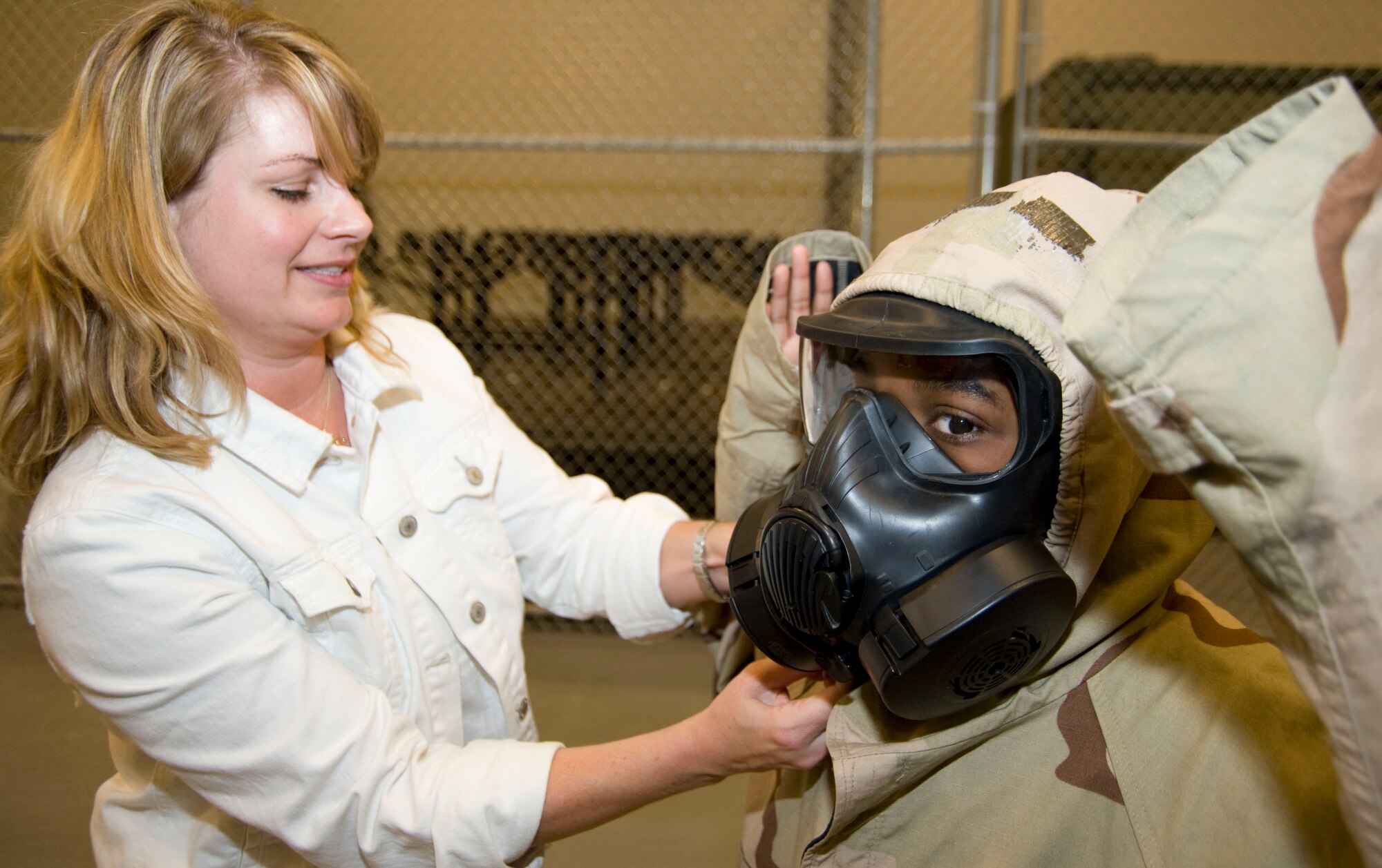 Senior Airman Marie Zieman, 403rd Civil Engineering Squadron emergency management readiness apprentice, adjusts the hood on the Chemical Protective Overgrment worn by J-Maxwell Irvin, son of Lt. Col. Marshall Irvin Jr., 403rd Mission Support Group commander. Participants in the Herc Day event donned chemical protective gear and masks at the Equipment/Readiness station, simulating some of the Mission Oriented Protective Postures reservists train under.