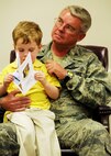 Holding his son, Josh, Air Force Reserve Col. Donald Buckley listens to comments during his assumption of command ceremony April 10 at Duke Field.   As the new 919th Operations Group commander, the colonel will report to the 919th Special Operations Wing commander on all operational matters for Reserve squadrons operating Air Force Reserve Command-owned MC-130E Combat Talon I aircraft, active-duty-owned U-28 aircraft and MQ-1 Predator remotely piloted aircraft. (U.S. Air Force photo/Tech. Sgt. Samuel King Jr.)
