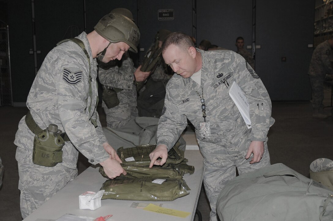 On April 10, 2010, during an Operational Readiness Exercise held in the Supply building of the 132d Fighter Wing in Des Moines, Iowa, Master Sgt. Ron Brand (right) assists Technical Sgt. Jeff Jorgenson (left) in reviewing the contents of his mobility bag before packing it up for travel.  This particular mobility bag is also called the C1 bag; it contains items such as Chemical Protective Overgarment (CPO) coats, CPO trousers, M8 paper, M9 tape, etc.  (US Air Force photo/Staff Sgt. Linda E. Kephart)(Released)