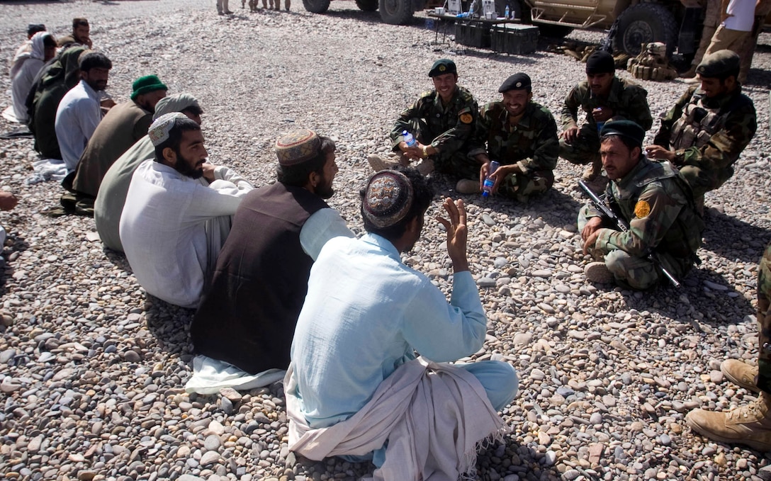 Afghan National Army soldiers answer questions from local citizens prior to the start of Nawa’s first-ever ANA recruiting and information event at Patrol Base Jaker April 12.  More than 60 people attended the event to hear about the benefits of military service.