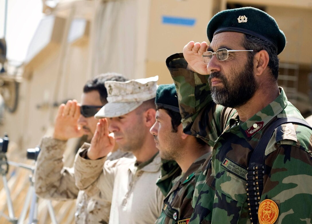 Col. Ali Ahmad, an Afghan National Army cultural and religious advisor, and other ANA and Marine Corps officers render a salute as a squad of ANA soldiers passes in review during a close order drill demonstration at Nawa’s first-ever ANA recruiting and information event April 12.  More than 60 people attended the event at Patrol Base Jaker to hear about the benefits of military service.