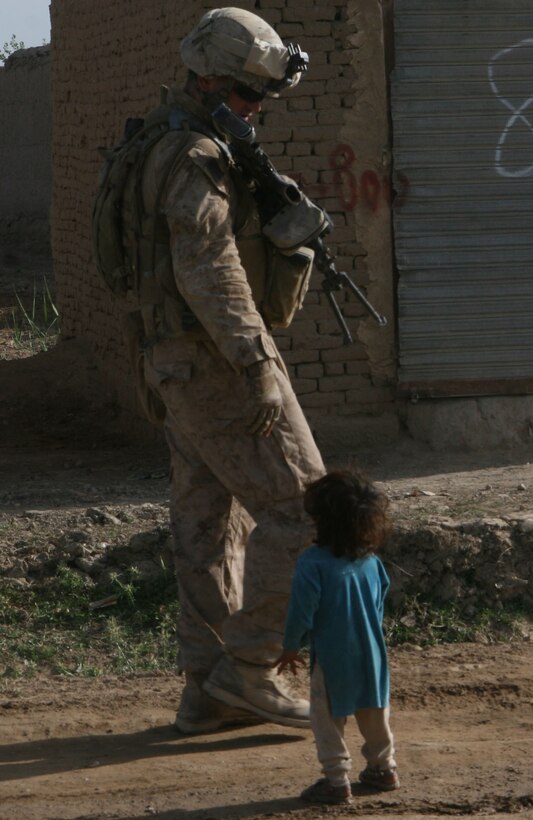 A Marine passes an Afghan child asking for food and water, while on a foot patrol near the government center in Marjah, Afghanistan, April 13. Marines and Afghan National Army soldiers with 1st Battalion, 6th Marine Regiment are taking part in the Marjah Accelerated Agricultural Transition program, which is a project aimed at facilitating the transition from illicit to licit crops,