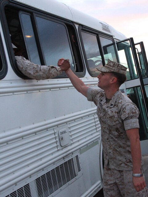 Cpl. Christophe Shelton, a heavy equipment operator for Support Company, 3rd Combat Engineer Battalion, says goodbye to a friend through a bus window before the unit departs for Afghanistan April 12 outside the battalion headquarters.