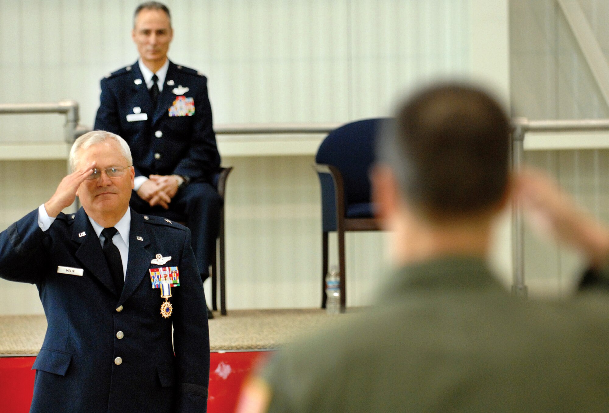 During the change of command ceremony at the C-17 hangar at March ARB, March 27, outgoing wing commander of the 452nd Air Mobility Wing, Brig. Gen. James L. Melin (left), receives a final salute from the 452nd Operations Group Commander, Col. Jeff Pennington, as the newly appointed 452 AMW Commander, Col. Udo Karl McGregor, watches from his seat on the stage. (U.S. Air Force photo by Staff Sgt. Stephen Schester)