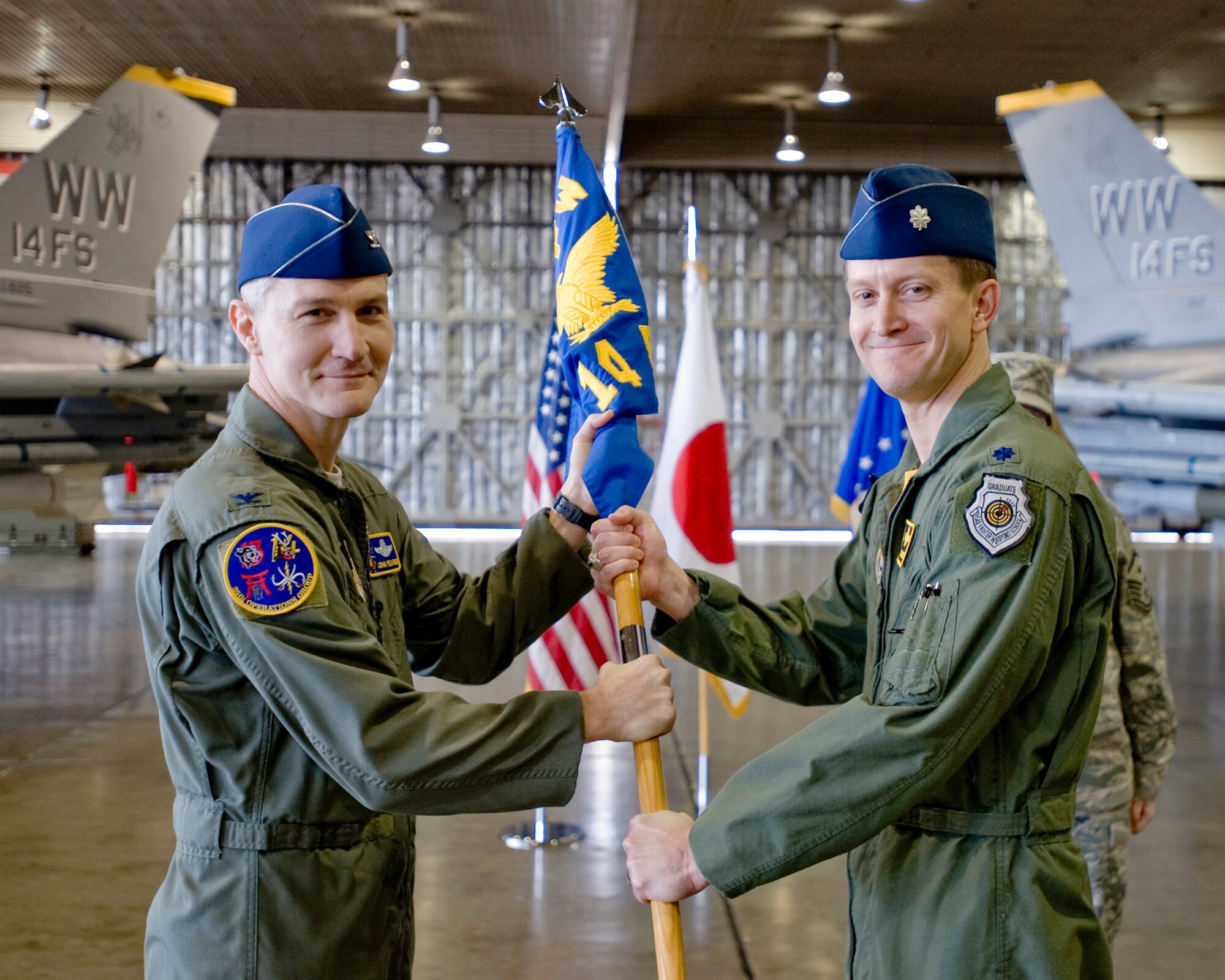 MISAWA AIR BASE, Japan -- Lt. Col. Aaron Steffens, former 35th Fighter Wing chief of safety, receives the 14th Fighter Squadron guidon from Col. John Pearse, 35th Operations Group commander, during a change of command ceremony April 9 at Hangar 911. Colonel Steffens assumed command of the squadron from Lt. Col. Shane Riza. (U.S. Air Force photo/Senior Airman Jamal D. Sutter)