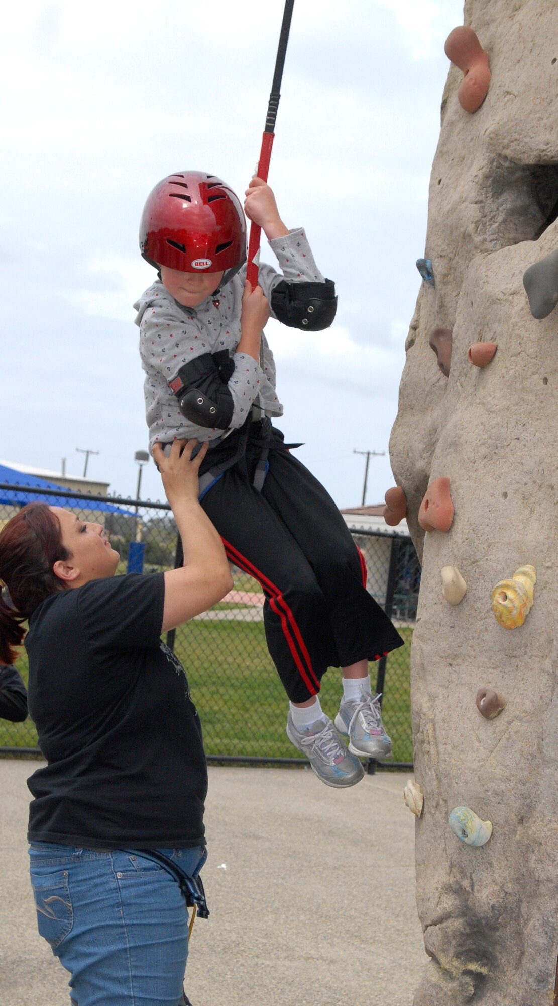 VANDENBERG AIR FORCE BASE, Calif. -- Ariana Cordero, an event volunteer, helps a military dependent climb a rock wall during Skate-a-Palooza at the Vandenberg Skate Park here Saturday, April 10, 2010. During Skate-a-Palooza Team V got a chance to skate, climb rock walls, and enjoy free food. (U.S. Air Force photo/Senior Airman Ashley Reed)