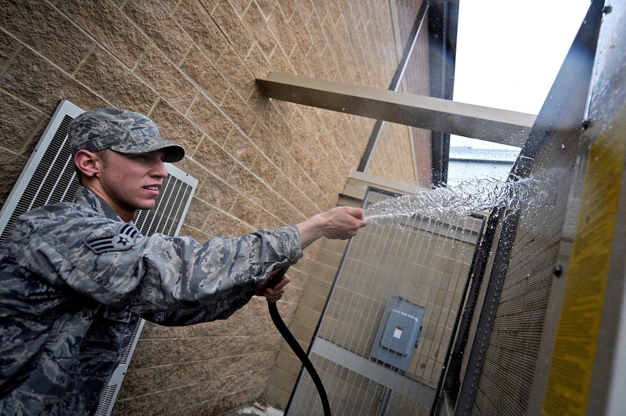ELLSWORTH AIR FORCE BASE, S.D. -- Senior Airman Brandon Bolden, 28th Civil Engineer Squadron heating, ventilation and air conditioning journeyman, cleans the coils of an air conditioning unit, April 12. Airman Bolden is conducting general maintenance which prevents the unit from building up too much pressure, and possibly failing. (U.S. Air Force photo/Airman 1st Class Matthew Flynn)