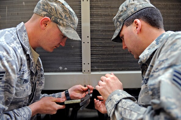 ELLSWORTH AIR FORCE BASE, S.D. -- (Left) Senior Airmen John Parris and Christopher Harris, 28th Civil Engineer Squadron heating, ventilation and air conditioning repair journeymen, attempt to remove a stripped screw from an air conditioning unit, April 12. Airmen Parris and Harris are performing general maintenance on the unit so it can continue to operate efficiently. (U.S. Air Force photo/Airman 1st Class Matthew Flynn)