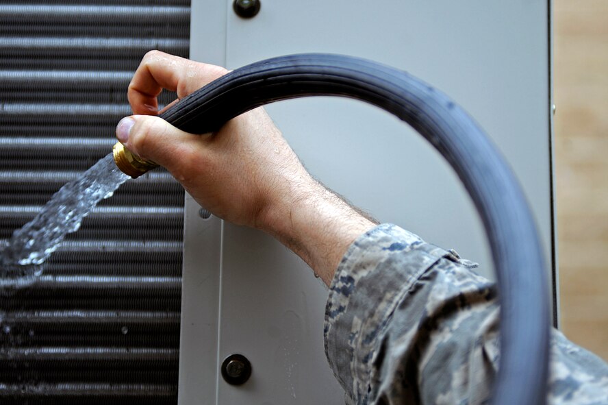 ELLSWORTH AIR FORCE BASE, S.D. -- Senior Airman Christopher Harris, 28th Civil Engineer Squadron heating, ventilation and air conditioning repair journeyman, cleans off coils of an air conditioning unit, April 12. HVAC personnel perform this monthly operation on air conditioning units around the base to ensure the unit functions at peak efficiency. (U.S. Air Force photo/Airman 1st Class Matthew Flynn)