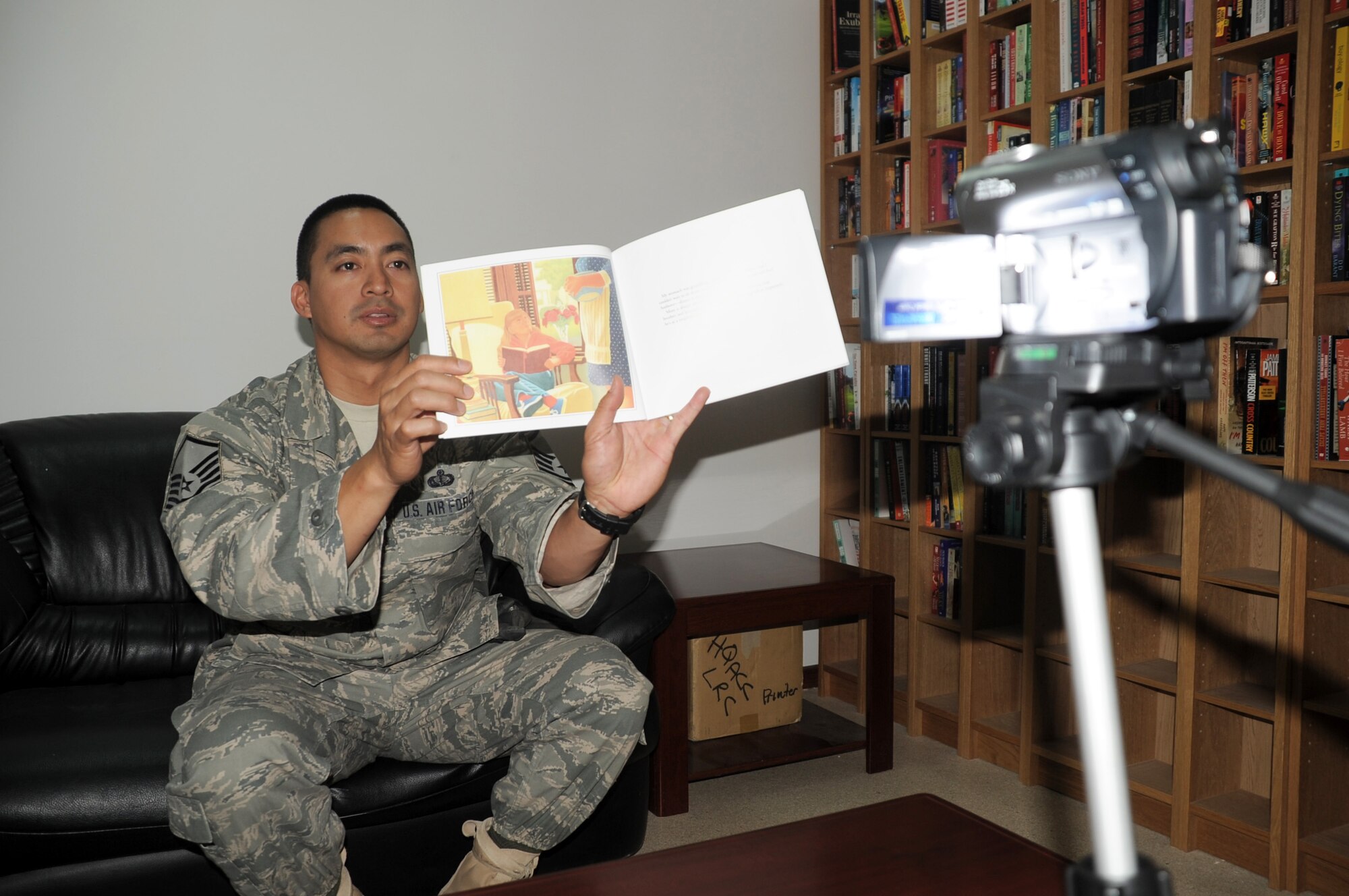 Master Sgt. Greg Ramos, services superintendent with the 380th Expeditionary Force Support Squadron, is video-recorded while reading a book for his children April 8, 2010, at a non-disclosed base in Southwest Asia. Sergeant Ramos was the second Airman at the 380th Air Expeditionary Wing to participate in the United Services Organization's United Through Reading program. The program allows for a deployed service member to read a book while being recorded and the book and a DVD is sent home to a child to see and follow along. Sergeant Ramos is deployed from the 154th Force Support Squadron at Hickam Air Force Base, Hawaii, and his hometown is Kapolei, Hawaii. (U.S. Air Force Photo/Master Sgt. Scott T. Sturkol/Released)