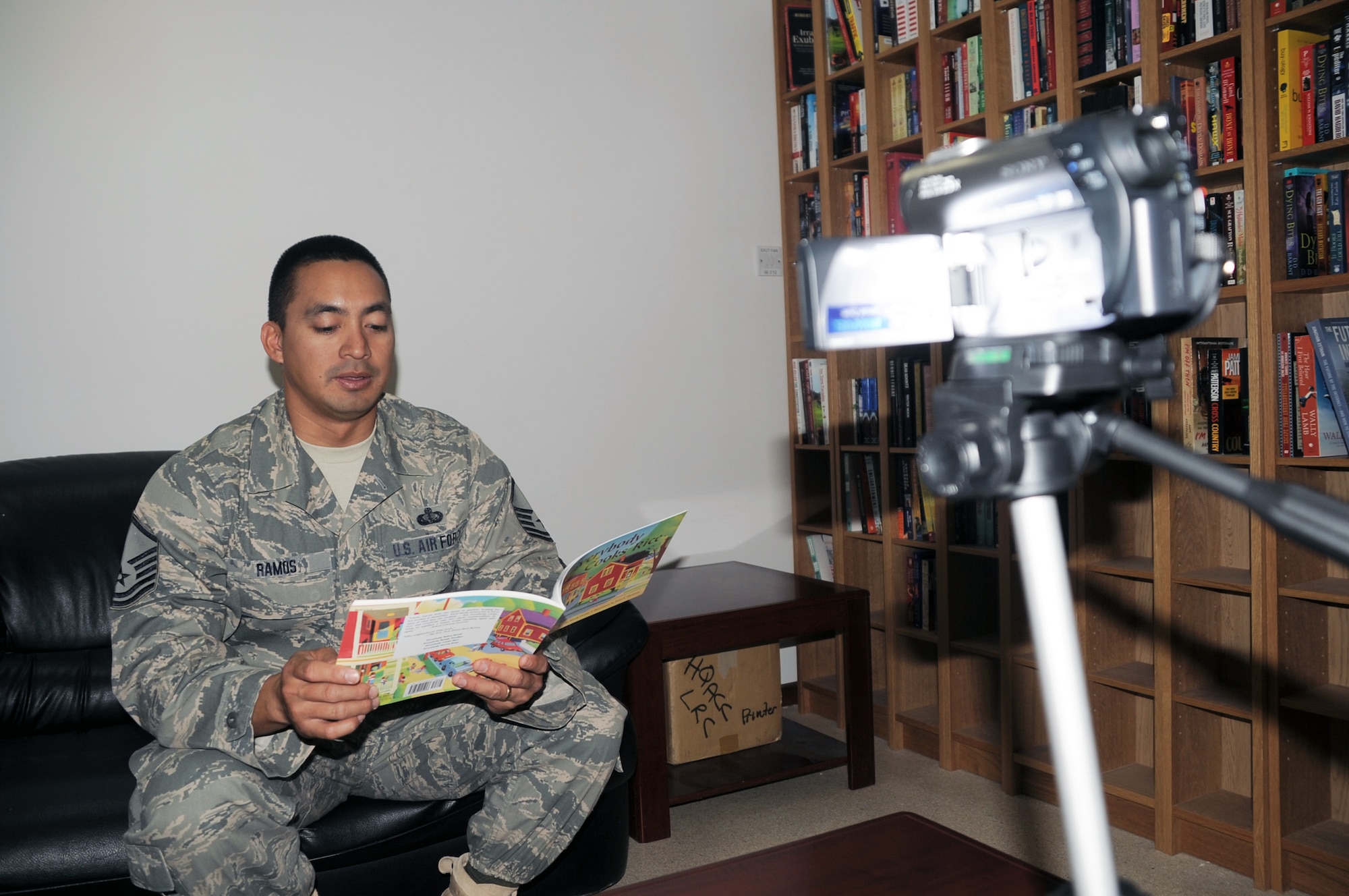 Master Sgt. Greg Ramos, services superintendent with the 380th Expeditionary Force Support Squadron, is video-recorded while reading a book for his children April 8, 2010, at a non-disclosed base in Southwest Asia. Sergeant Ramos was the second Airman at the 380th Air Expeditionary Wing to participate in the United Services Organization's United Through Reading program. The program allows for a deployed service member to read a book while being recorded and the book and a DVD is sent home to a child to see and follow along. Sergeant Ramos is deployed from the 154th Force Support Squadron at Hickam Air Force Base, Hawaii, and his hometown is Kapolei, Hawaii. (U.S. Air Force Photo/Master Sgt. Scott T. Sturkol/Released)