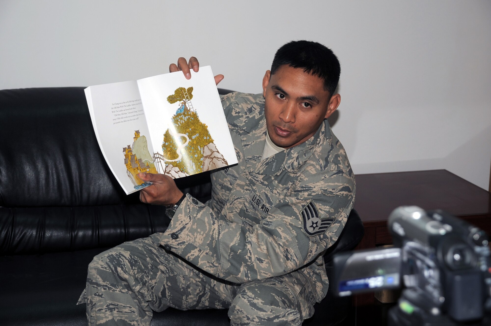 Staff Sgt. Gavin Ramos, services journeyman with the 380th Expeditionary Force Support Squadron, is video-recorded while reading a book for his children April 8, 2010, at a non-disclosed base in Southwest Asia. Sergeant Ramos was the first Airman at the 380th Air Expeditionary Wing to participate in the United Services Organization's United Through Reading program. The program allows for a deployed service member to read a book while being recorded and the book and a DVD is sent home to a child to see and follow along. Sergeant Ramos is deployed from the 154th Force Support Squadron at Hickam Air Force Base, Hawaii, and his hometown is Kapolei, Hawaii. (U.S. Air Force Photo/Master Sgt. Scott T. Sturkol/Released)