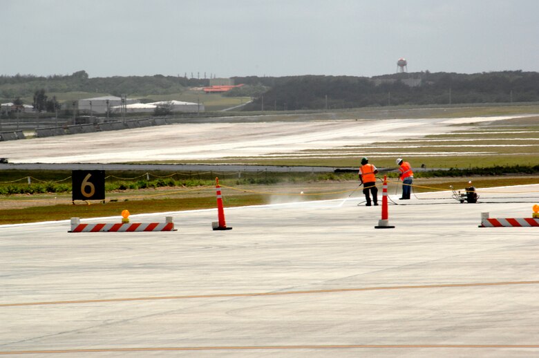 ANDERSEN AIR FORCE BASE, Guam - Construction workers pressure-wash a recently completed section of the South Runway. The runway is slated to re-open in mid-May and will bring added capability and safety improvements to Andersen operations. Starting April 15, all aircraft and vehicle operators will have to request approval enter or to access the controlled movement area surrounding the South Runway from the tower via two-way radio and be trained in accordance with 36th Wing Instruction 13-201. (U.S. Air Force photo by Tech. Sgt. Mike Andriacco)