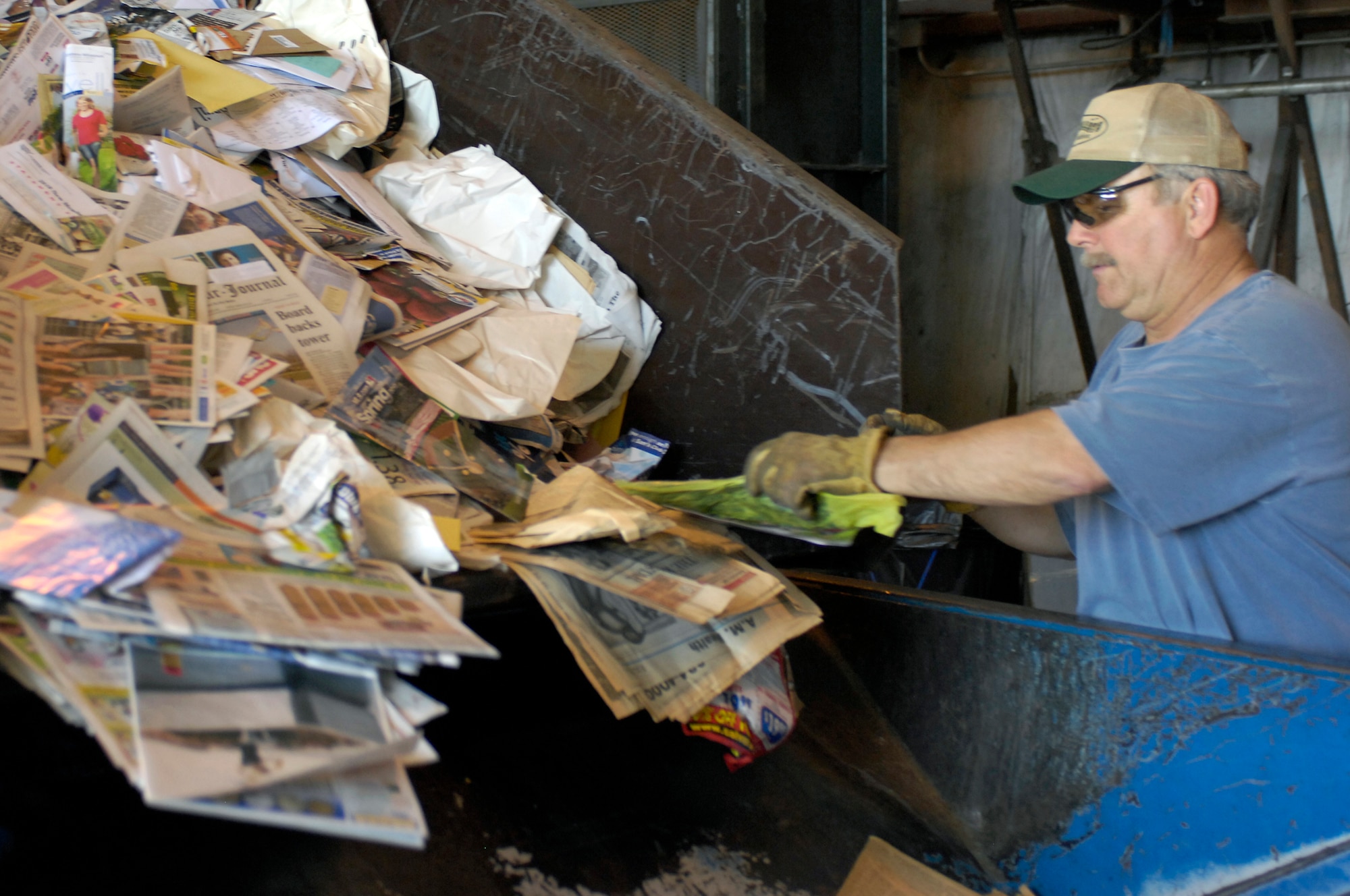 Mr. Mark Davis, Whiteman Recycling Center material examiner,pulls recyclable newspaper into a bailing machine April 12, 2010, to bail it for storage and sale. Recyclable materials are separated and bailed according to the type of material. (U.S. Air Force photo/Staff Sgt. Jason Barebo) 
