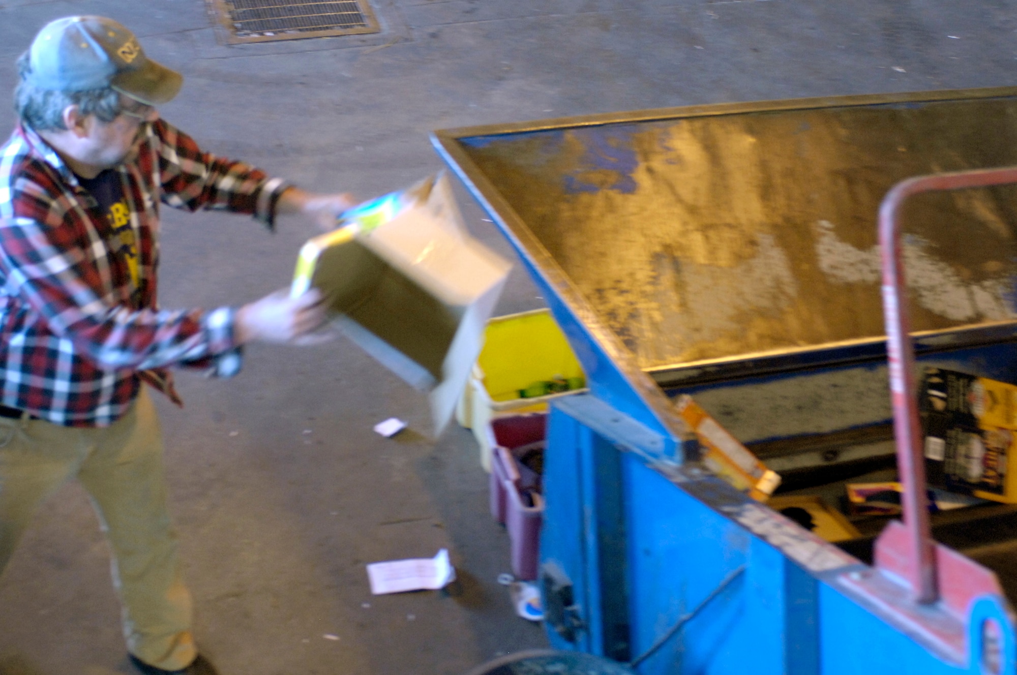 Mr. David Ritter, Whiteman Recycling Center material examiner, tosses cardboard into a crusher machine to process it for bailing. Each bail of cardboard weighs more than 1,000 tons. (U.S. Air Force photo/Staff Sgt. Jason Barebo)