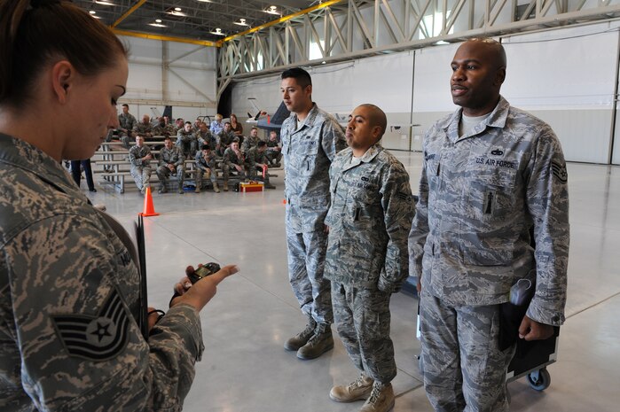 CREECH AIR FORCE BASE, Nev. -- Tech Sgt. Marcy Holland, tracked the time with a stop watch of the weapons loading competition as (left to right) Senior Airman Domingo Morales, Senior Airman Valerio Morales, and Staff Sgt. Roddrick Palmore, weapons loaders assigned to 432nd Aircraft Maintenance Squadron, stand at attention to stop the timer, April 12, 2010, during the 432d AMXS load crew of the quarter competition (U.S. Air Force Photo by Airman 1st Class Brett Clashman)
