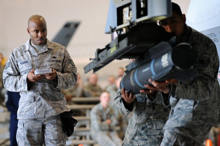 CREECH AIR FORCE BASE, Nev. --  Staff Sgt. Roddrick Palmore observes as Senior Airman Freddy Morales, and Senior Airman Valerio Mendoza, load an inert AGM-114 Hellfire II air-to-ground missile onto a Reaper during the 432d Aircraft Maintenance Squadron load crew of the quarter competition April 12, 2010. MQ-9 Reaper weapons loaders assigned to the 432d AMXS. (U.S. Air Force photo by Tech. Sgt. Michael R. Holzworth)
