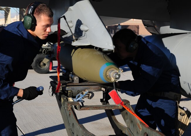 NELLIS AIR FORCE BASE, Nev. -- Airman 1st Class Brian Woollard and Staff Sgt. Robert Rodriguez, load crew members from 57th Aircraft Maintenance Squadron, load a bomb onto an F-16 Falcon during a  load crew competition April 9, 2010.   (U.S. Air Force Photo by Staff Sgt. William P. Coleman)
