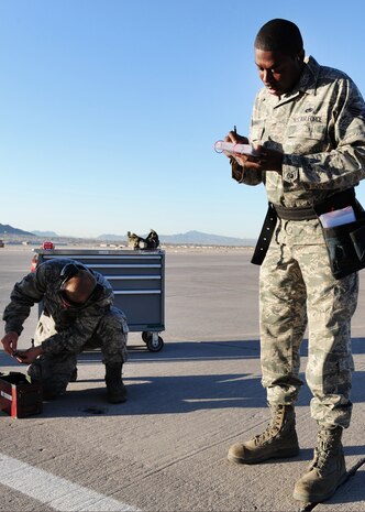 NELLIS AIR FORCE BASE, Nev. -- Senior Airman Brendon Howbert gathers tools while Staff Sgt. Cir Thomas reads a check list.  Both are 757th Aircraft Maintenance Squadron load crew members participating in the 57th Maintenance Group load crew competition, April 9, 2010.    (U.S. Air Force Photo by Staff Sgt. William P. Coleman)
