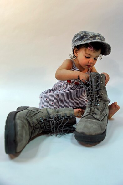ELLSWORTH AIR FORCE BASE S.D. -- The daughter of an Ellsworth Airman plays with her father’s hat and boots, April 8.   April has been designated as the Month of the Military Child.  This month-long celebration was created by former Defense Secretary Caspar Weinberger in 1986. (U.S. Air Force photo/Senior Airman Marc I. Lane)