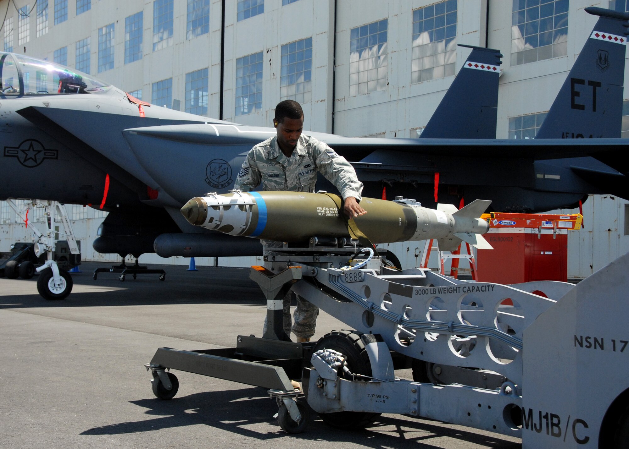 Staff Sgt. Chris Nelloms, 46th Test Wing, maneuvers a bomb into place prior to attaching it to an aircraft on display at the 75th Anniversary Air Show April 11. More than 125,000 were in attendance during the air show April 10-11, enjoying a variety of aerial performances and static displays. This is Eglin’s first open house since 2007 and was timed to coincide with the 75th anniversary of the installation. The F-22A Raptor demo, Army Black Daggers and "Tora, Tora, Tora" were some of the highlights of the event. (U.S. Air Force photo/ Samuel King Jr.)