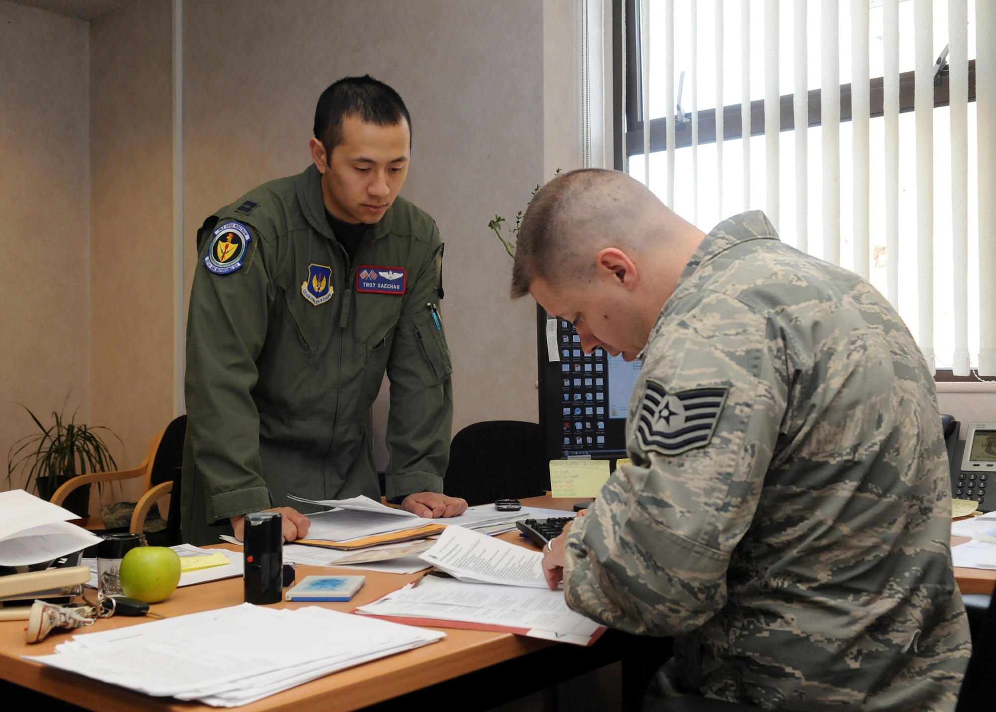 RAF MILDENHALL, England – Capt. Troy Saechao, 351st Air Refueling Squadron, waits for Tech. Sgt. George Wolf, 100th Force Support Squadron non-commissioned officer in charge of personnel readiness, to verify his deployment paperwork is in order prior to leaving April 13.  Sergeant Wolf receives and distributes all taskings to RAF Mildenhall Airmen and ensures all training and eligibility requirements are met.  (U.S. Air Force photo/ Staff Sgt. Jerry Fleshman)