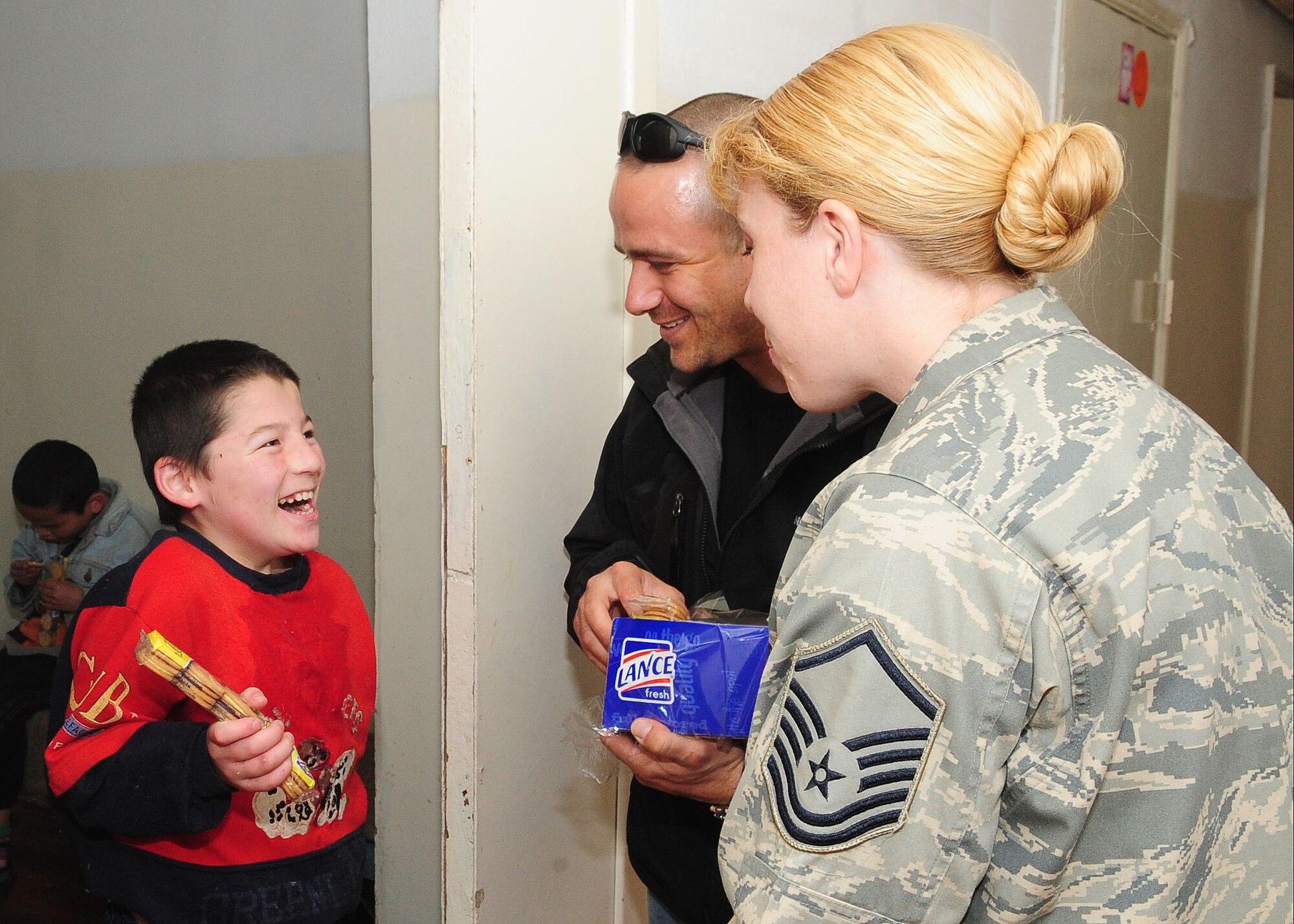 U.S. Air Force Master Sgt. Laurie Boros and Jeff Villemarette bring a smile to the face of a young boy at the Belovodsky Orphanage April 13, 2010. U.S. Airmen from the Transit Center collected 8,000 COM (almost $200) and bought the orphanage basic items including sugar, rice, beans, tea, clothing and other necessities. Some donations were also given by Americans stateside for this and other humanitarian assistance projects in the city and surrounding areas. (U.S. Air Force photo/Senior Airman Nichelle Anderson/released)