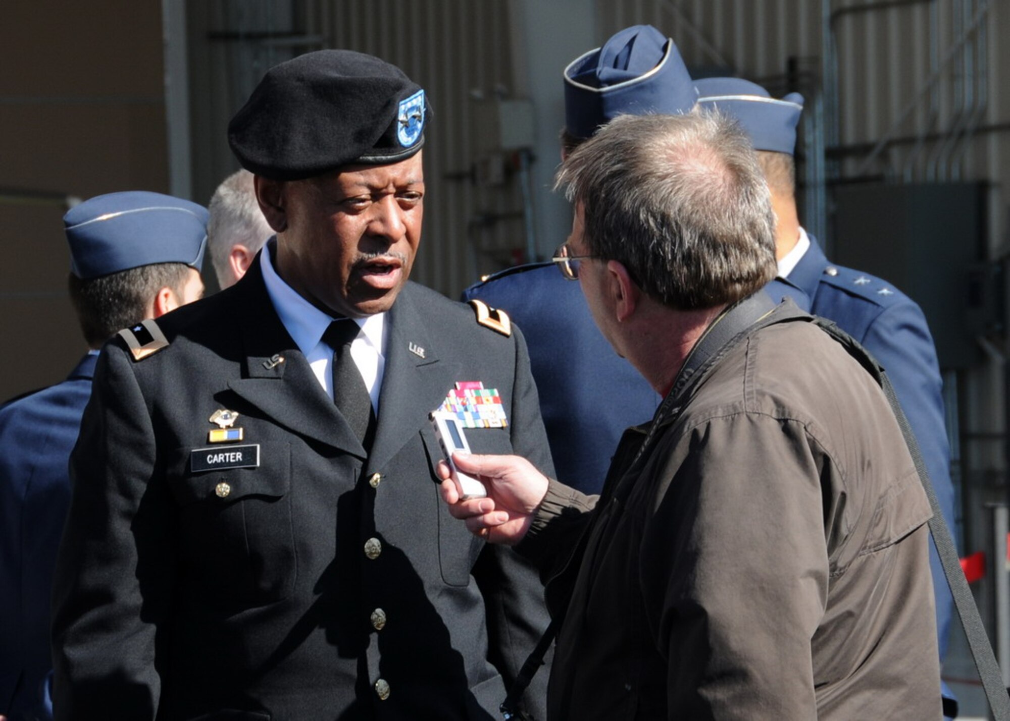 Maj. Gen.  Joseph Carter, the MA Adjutant General, is interviewed by Westfield News photographer Mr. Fred Gore in front of the new Air Sovereignty Alert hangar at the 104th Fighter Wing, Massachusetts Air National Guard base in Westfield Massachusetts on April 10, 2010 just after the official ribbon cutting ceremony.  The wing officially accepted the alert mission on February 15, 2010, and stands ready to defend the homeland if called upon.  (photograph by Senior Master Sgt. Robert J. Sabonis)