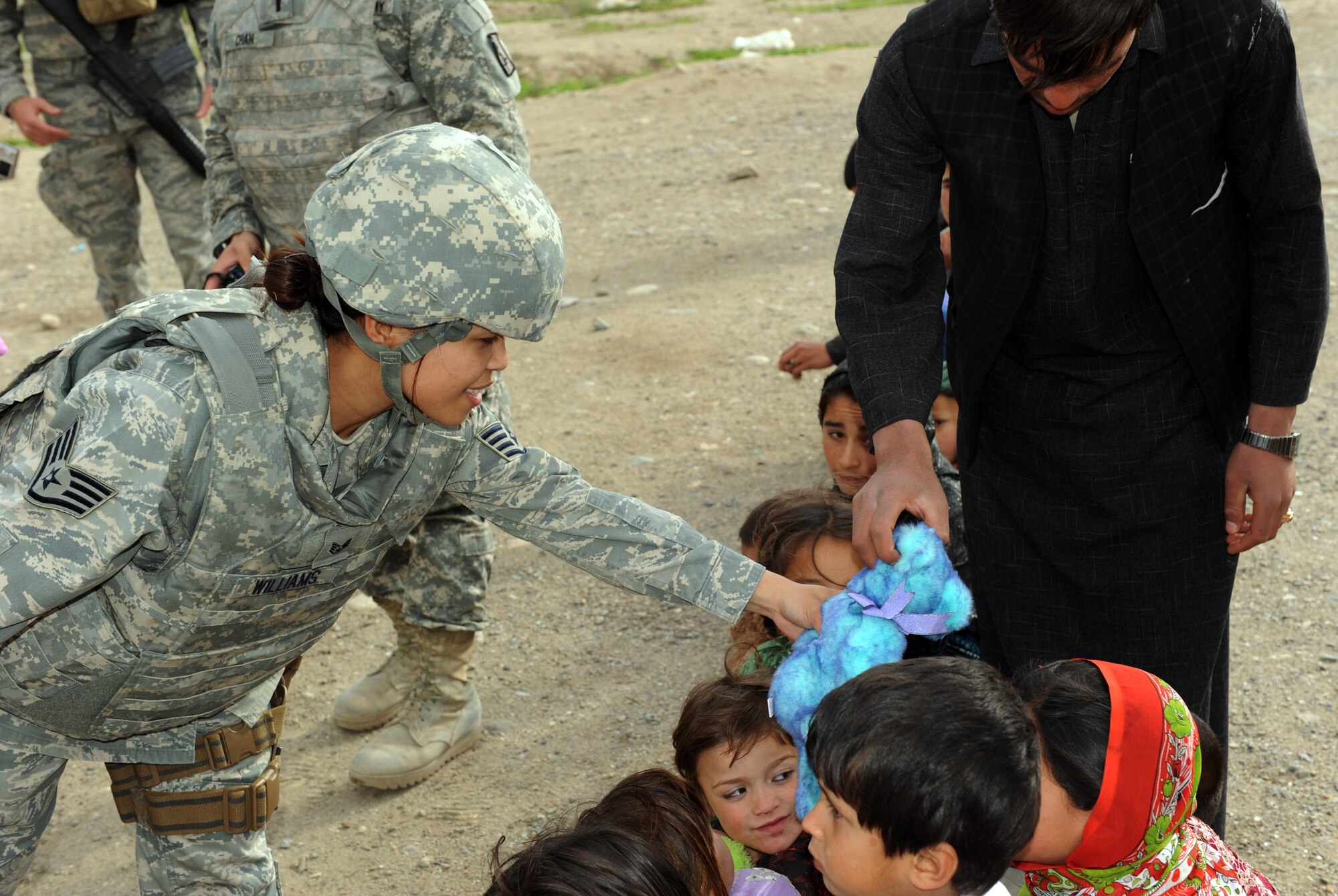 U.S. Air Force Staff Sgt. Charissa Williams, 755th Air Expeditionary Group, hands out stuffed animals to local children during an Operation Care humanitarian aid mission at Bagram Airfield, Afghanistan. Sergeant Williams is deployed from Misawa Air Base, Japan, and is a San Antonio, Texas native. (U.S. Air Force photo by/Staff Sgt. Richard Williams)