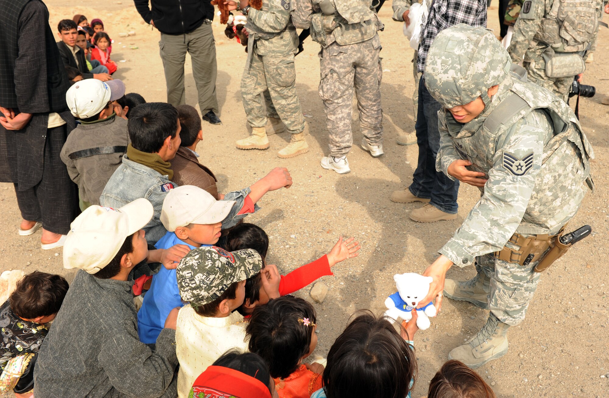 U.S. Air Force Staff Sgt. Charissa Williams, 755th Air Expeditionary Group, hands out stuffed animals to local children during an Operation Care humanitarian aid mission at Bagram Airfield, Afghanistan. Sergeant Williams is deployed from Misawa Air Base, Japan, and is a San Antonio, Texas native. (U.S. Air Force photo by/Staff Sgt. Richard Williams)