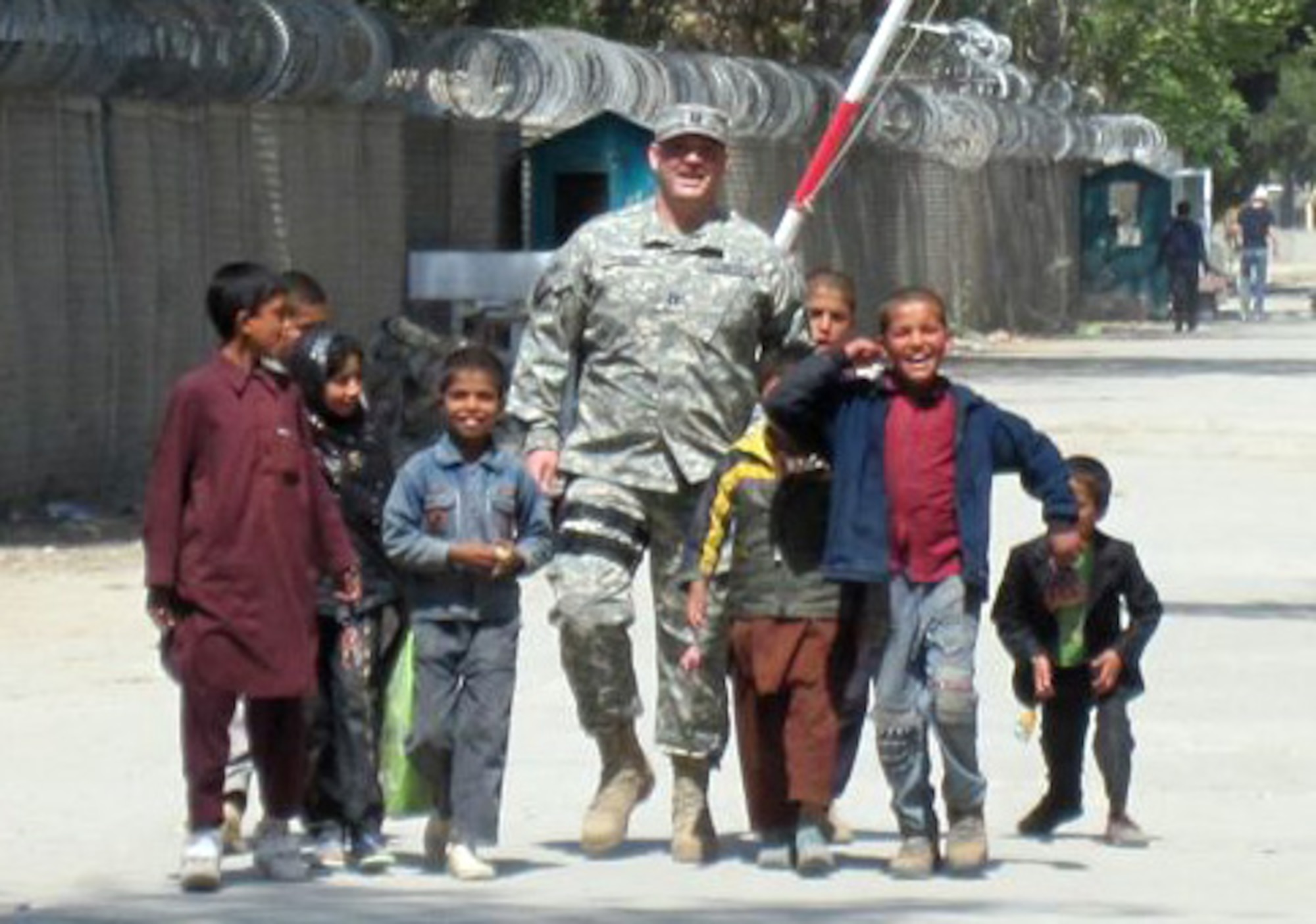 AFGHANISTAN -- Capt. Adam Pudenz, 460th Force Support Squadron, walks near a refugee camp with Afghan children. Anyone wanting to donate shoes, school supplies or other items can stop by the Airman and Family Readiness Center. (Courtesy photo)