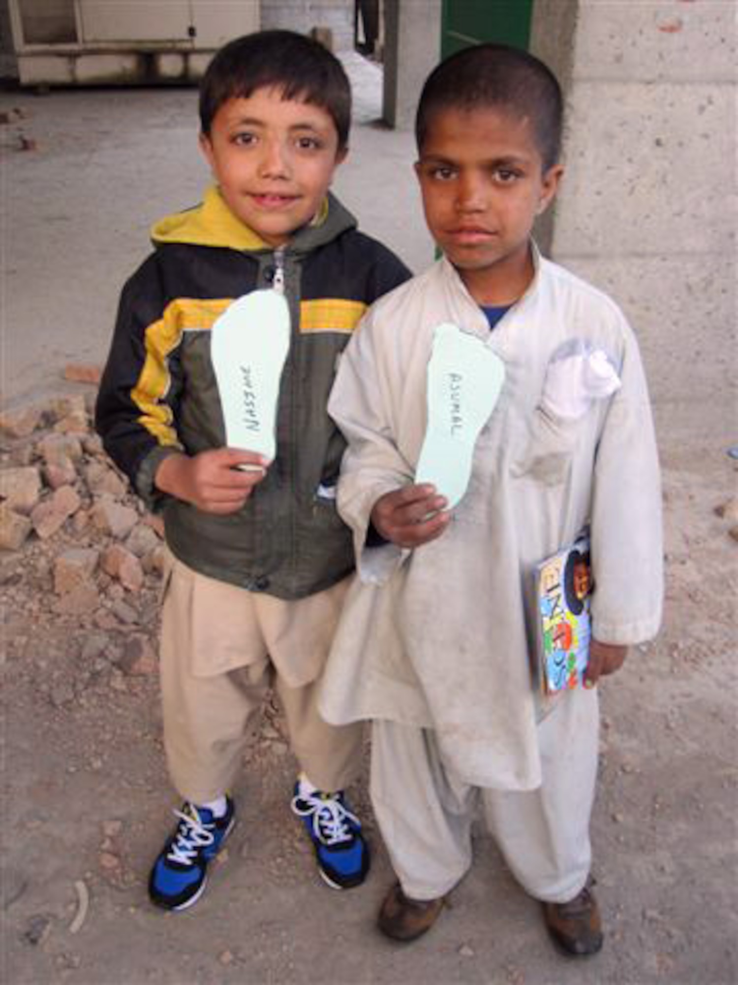 AFGHANISTAN -- Nasime and Ajumal, two Afghan refugee children, mug for Capt. Adam Pudenz, 460th Force Support Squadron. The children are wearing donated shoes collected by the Company Grade Officer Council. (Courtesy photo)