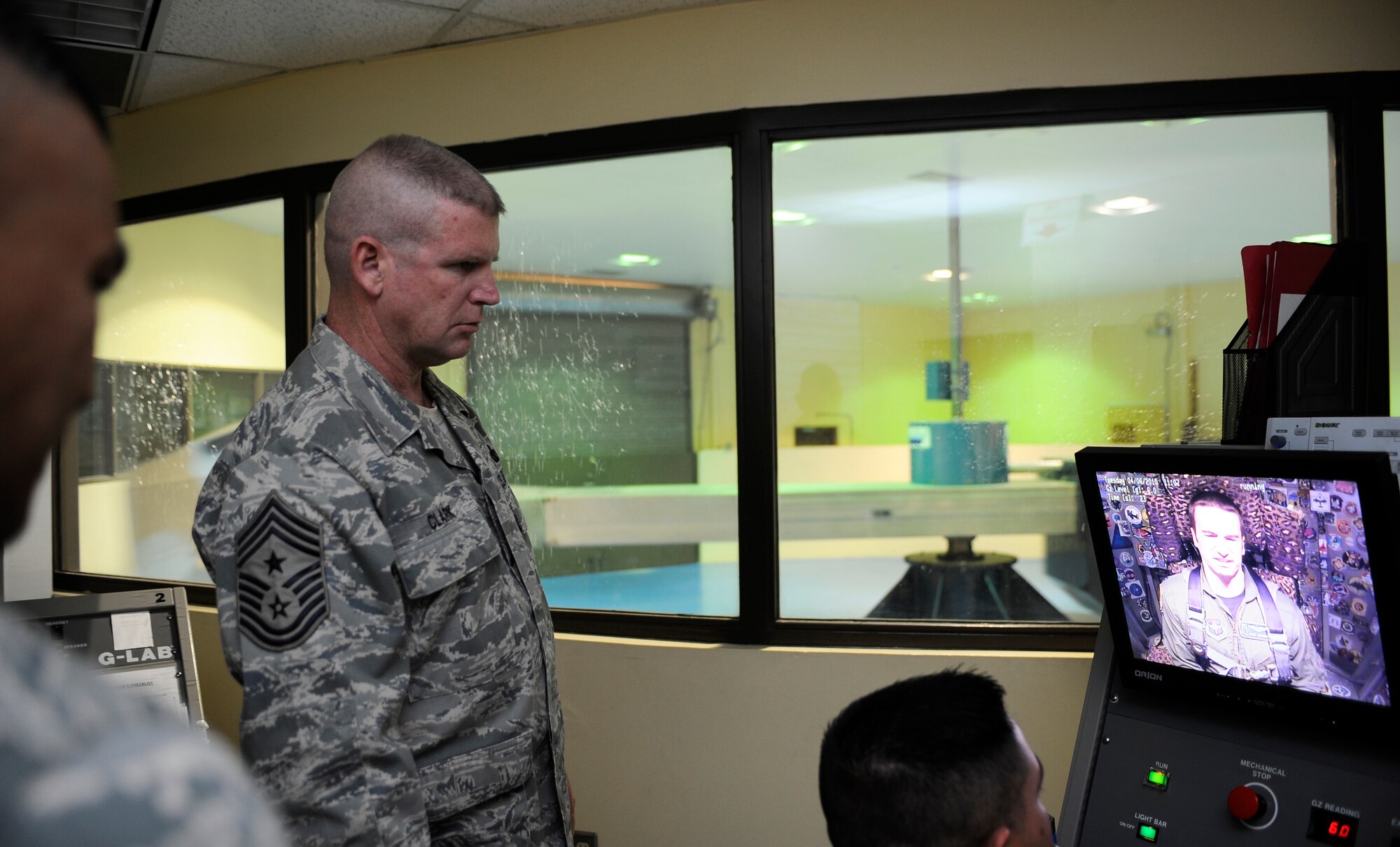 HOLLOMAN AIR FORCE BASE, N.M. -- Chief Master Sgt. Harold Clark, 12th Air Force command chief, watches as Capt. Joshua Higgins practices the anti-gravity straining maneuvers inside a centrifuge at the Physiological Training Center April 6, 2010. Master Sgt. Gregory Flores lectures Capt. Higgins on isometric muscle contractions that train Aircrew on the effects of high anti-gravity straining maneuvers. (U.S. Air Force photo by Airman 1st Class Veronica Stamps / Released)