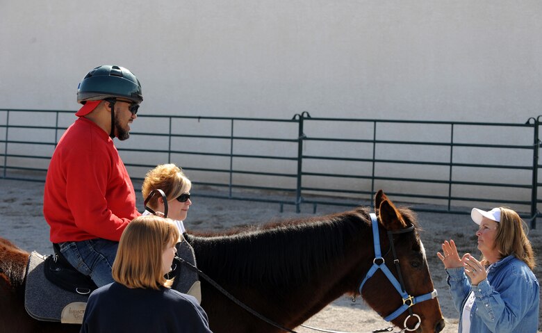 Laurie Willmott (right), owner and founder of Spirit Therapies in Las Vegas, Nev., and several volunteers teach Kim Tanner, a retired Army transportation specialist, the art of horseback riding as part of the Horses Healing Heroes program. He sustained severe injuries after being struck by an improvised explosive device in Iraq in 2005. The program serves active-duty military and veterans who have been diagnosed with physical and or mental challenges. (U.S. Air Force photo/Master Sgt. Kevin J. Gruenwald)