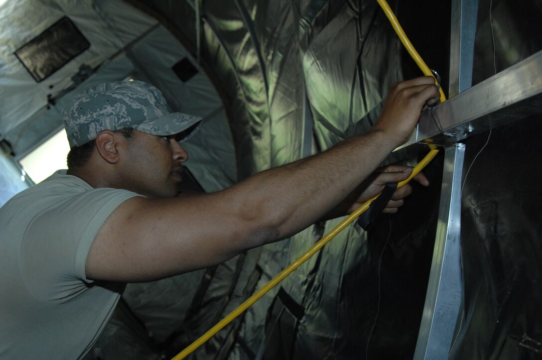 Airman 1st Class Christopher Taylor, 316th Civil Engineer Squadron structural apprentice, removes hanging lights inside a small shelter system personnel tent at Joint Base Andrews, Md., April 14, 2010. Members of the 316 CES broke the tent and other temporary locations around base down that supported Andrews staff working during the Nuclear Security Summit.  The 316th Wing led Joint Base Andrews in providing a transition location for a number of foreign national leaders arriving from around the world in attendance of the summit.  (U.S. Air Force photo by Staff Sgt. Christopher Marasky)