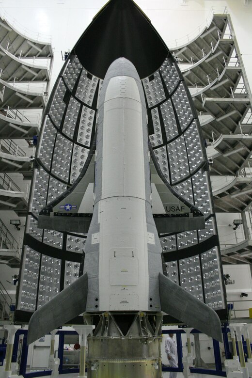 The first X-37B Orbital Test Vehicle waits in the encapsulation cell of the Evolved Expendable Launch vehicle April 5, 2010, at the Astrotech facility in Titusville, Fla. Half of the Atlas V five-meter fairing is visible in the background. (Courtesy photo)