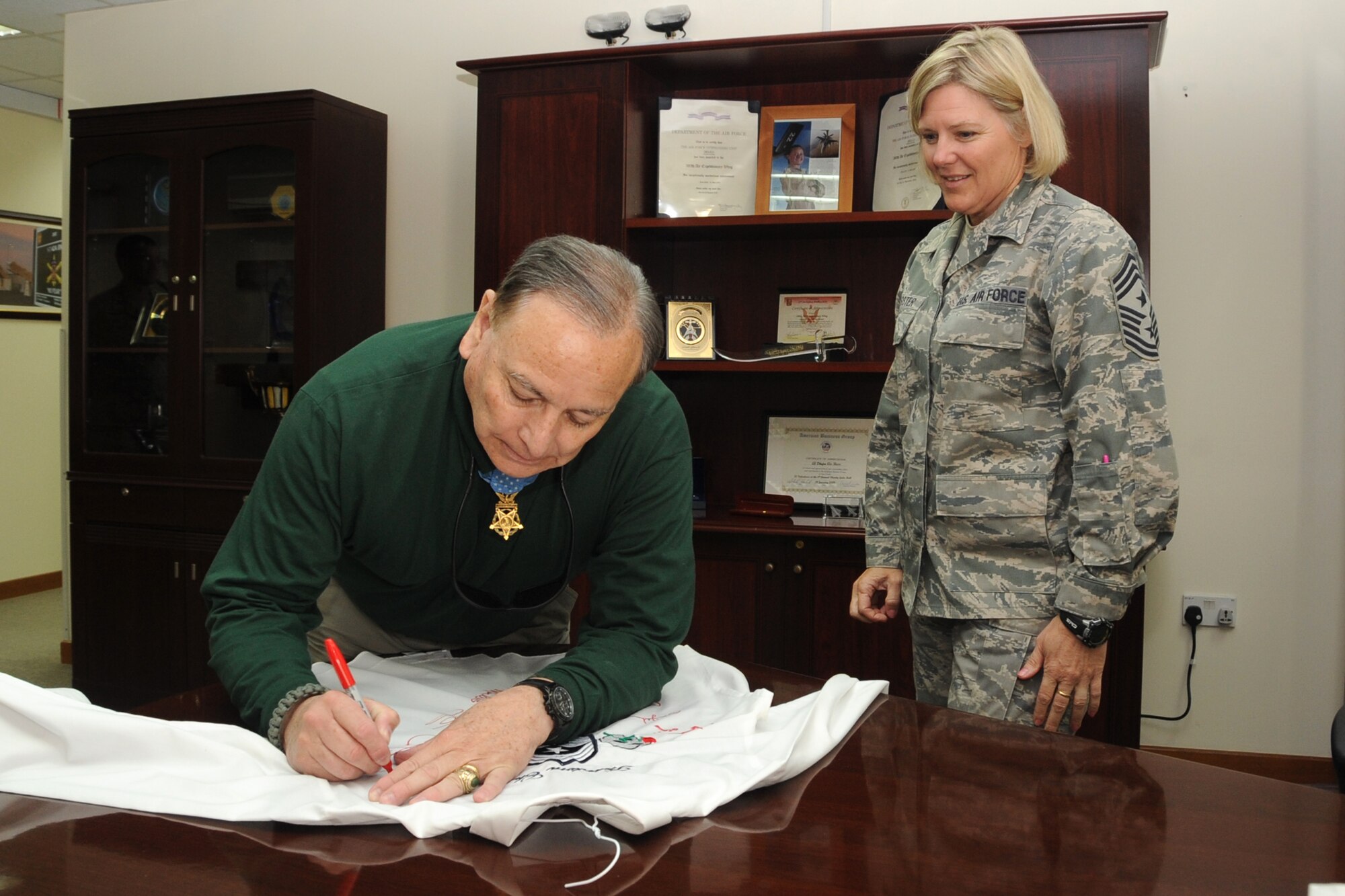 Medal of Honor winner Alfred V. Rascon signs a shirt for Command Chief Master Sgt. Suzan Sangster at an undisclosed location in Southwest Asia on April 12, 2010. The 380th Air Expeditionary Wing, supports Operations Iraqi Freedom and Enduring Freedom and the Combined Joint Task Force-Horn of Africa. The 380th AEW is comprised of four groups and 12 squadrons and the wing's deployed mission includes air refueling, surveillance and reconnaissance in support of overseas contingency operations in Southwest Asia. (U.S. Air Force photo/Senior Airman Jenifer H. Calhoun/Released)
