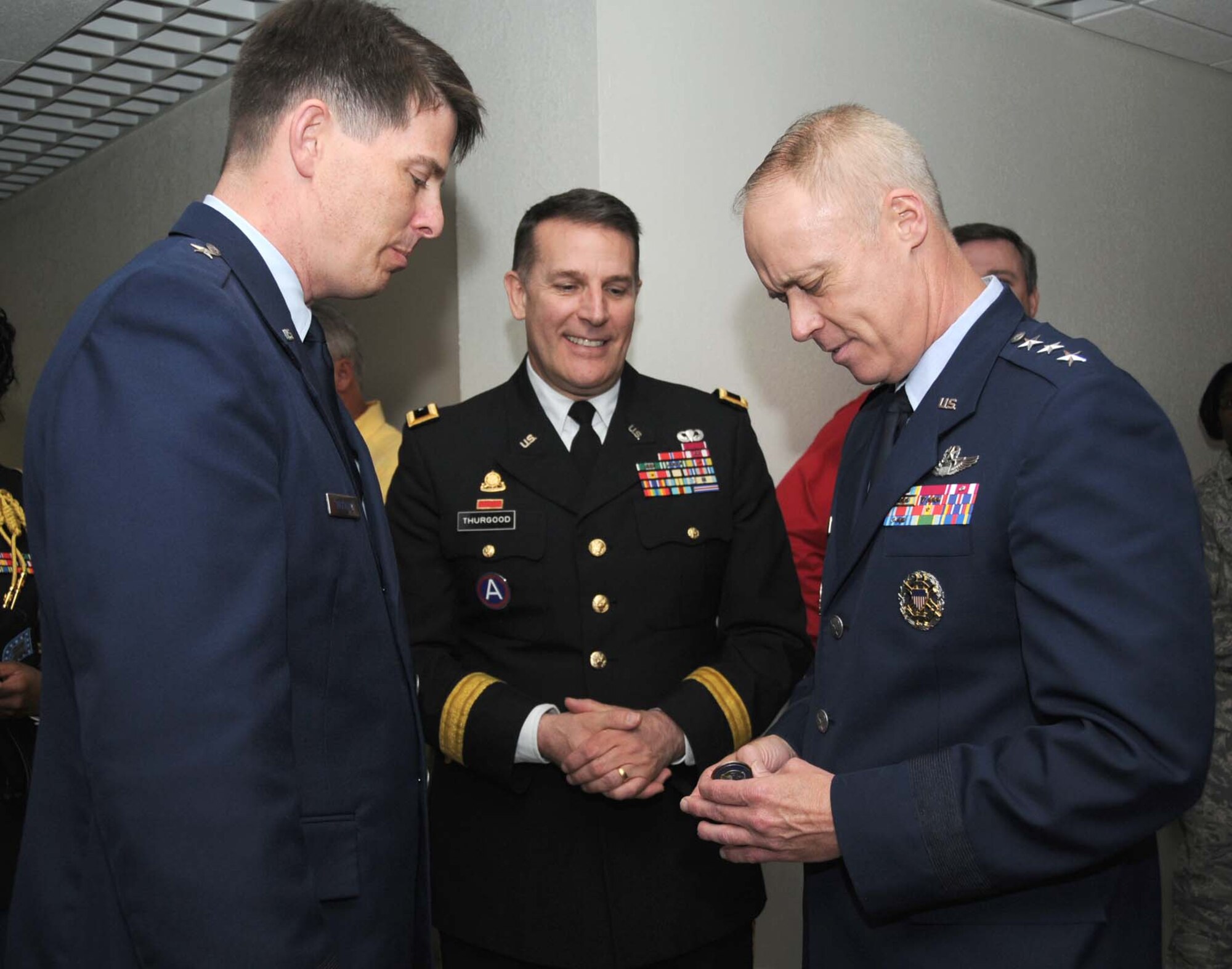 Brig. Gen. Ian Dickinson, left, 81st Training Wing commander, presents a wing coin to Lt. Gen. Richard Newton III, right, at Wolfe Hall April 6 as Army Maj. Gen. Keith Thurgood looks on.  General Newton is president of the board of directors for the Defense Commissary Agency, and General Thurgood is the commanding officer for the Army and Air Force Exchange Service.  Generals Newton and Thurgood attended a ribbon-cutting ceremony for a renovated second floor hallway in Wolfe Hall while at Keesler to participate in the opening of new base exchange and commissary shopping complex.  The renovation updated a circa-1976 training area for the 335th Training Squadron.  (U.S. Air Force photo by Kemberly Groue)
