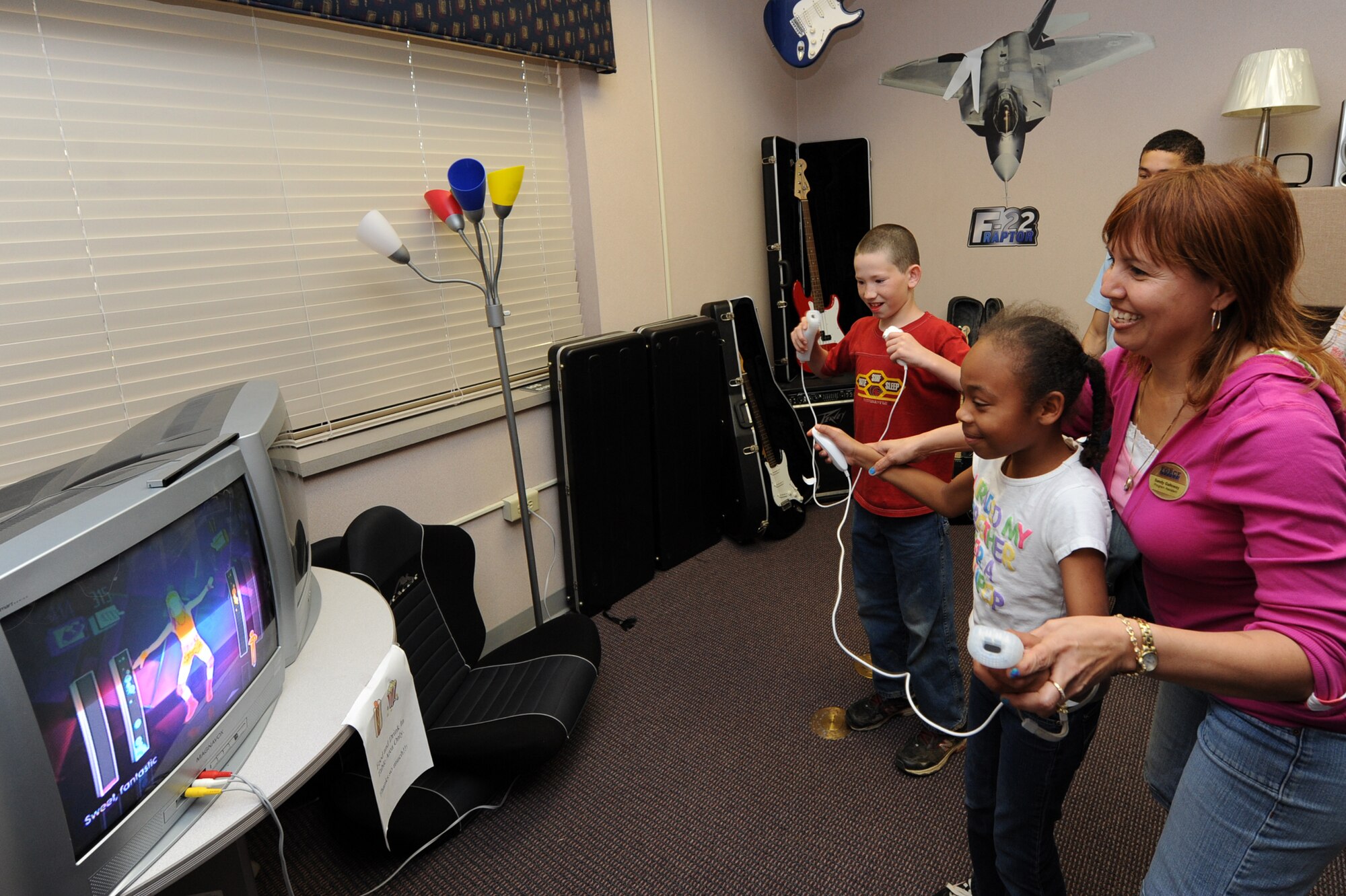 Sandy Galloway, 19th Force Support Squadron program assistant, plays an interactive video game with Tyerra Foster, 11, daughter of Capt. Miguel Rivera, 62nd Airlift Squadron; and Steven Rhodes, 11, at the Teen Center March 24. The facility has video game consoles with a wide variety of the most current video games. (U.S. Air Force photo by Senior Airman Ethan Morgan)