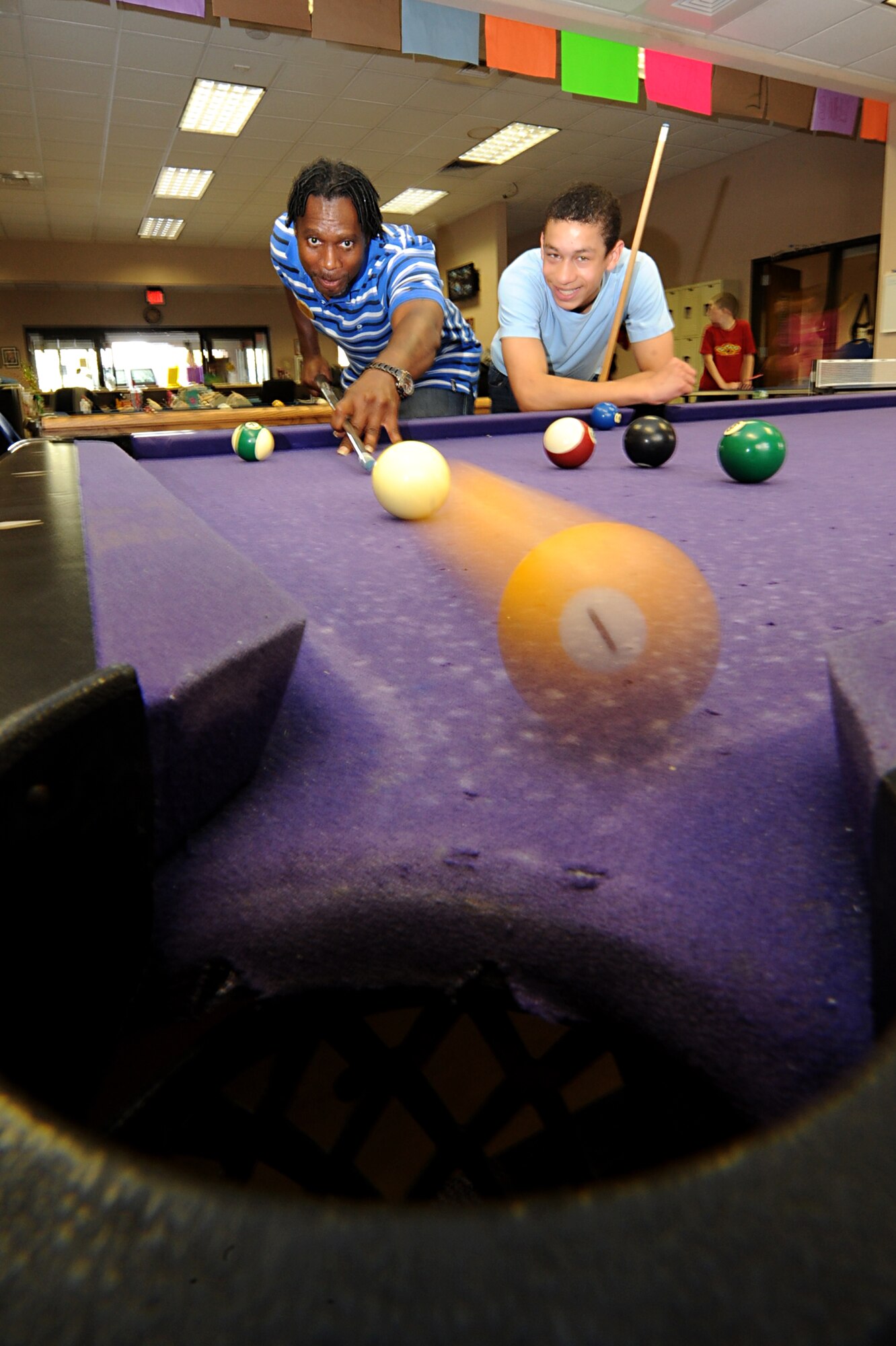 Al Nelson, 19th Force Support Squadron assistant youth director, plays a game of pool with Justin Perez, 13, son of Capt. Miguel Rivera, 62nd Airlift Squadron, at the Teen Center March 24. Pool is one of the many activities available for the teens to utilize while interacting with the facilities personnel. (U.S. Air Force photo by Senior Airman Ethan Morgan)