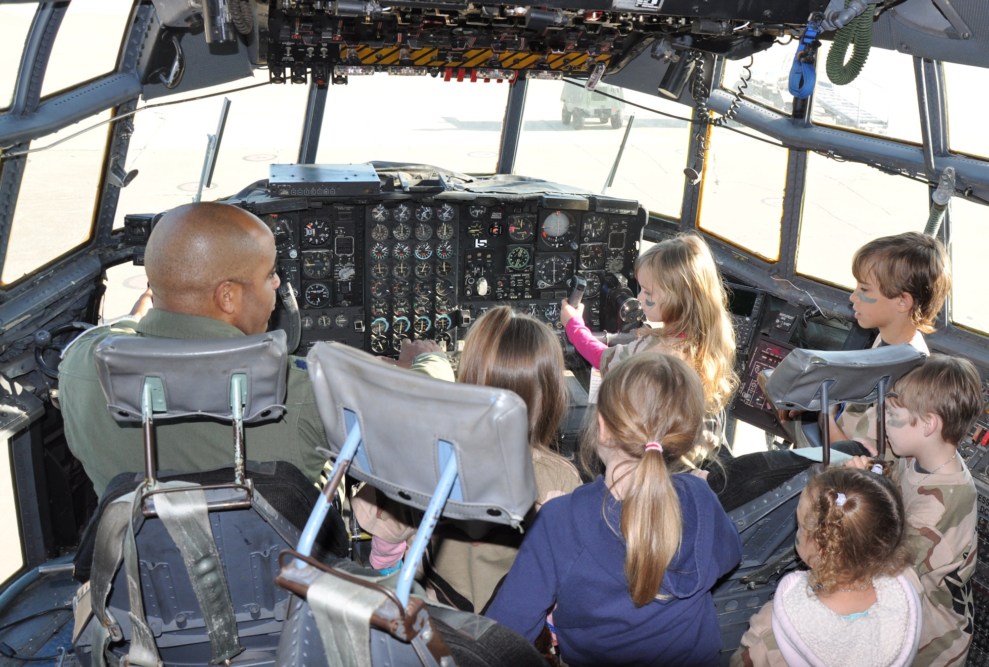 Children explore the cockpit of a C-130 trainer aircraft after arriving at their deployment destination, Base “X,” during the Operation KIDS event April 10. Lt. Col. Dave Leazer, 89th Flying Training Squadron operations officer, who piloted the aircraft during the trip, answers the children’s questions about the operation and controls of the aircraft. (U.S. Air Force Photo/Airman 1st Class Adawn Kelsey)
